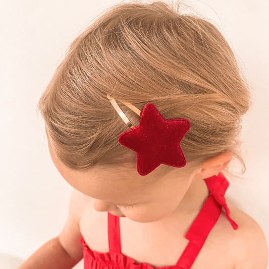 Girl wearing the Red Velvet Star Clip, featuring a deep red velvet star that measures about 7 cm. This elegant accessory adds a stylish accent to her hairstyle, perfect for special occasions or everyday wear.